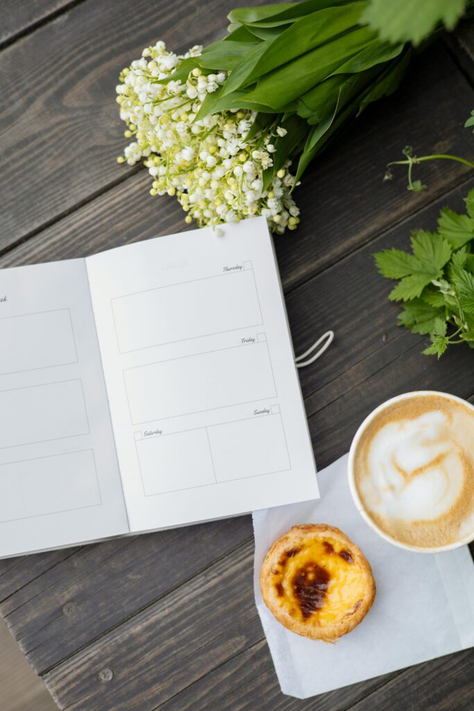 A cozy morning scene featuring a planner, cup of coffee, and a delicious pastry.